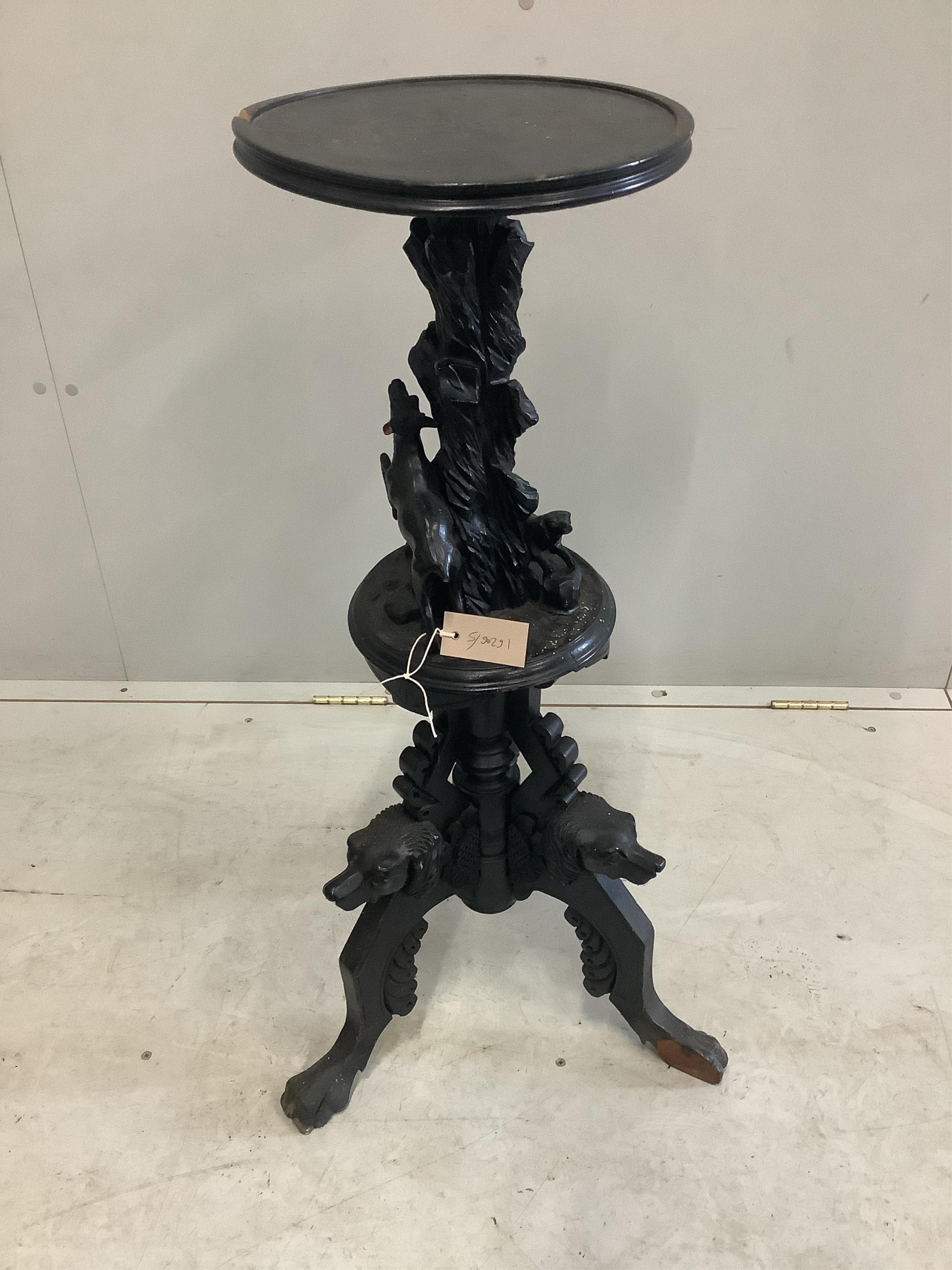 A late 19th century Black Forest ebonised wood urn stand carved with a running deer and hounds heads, height 90cm. Condition - poor, numerous losses